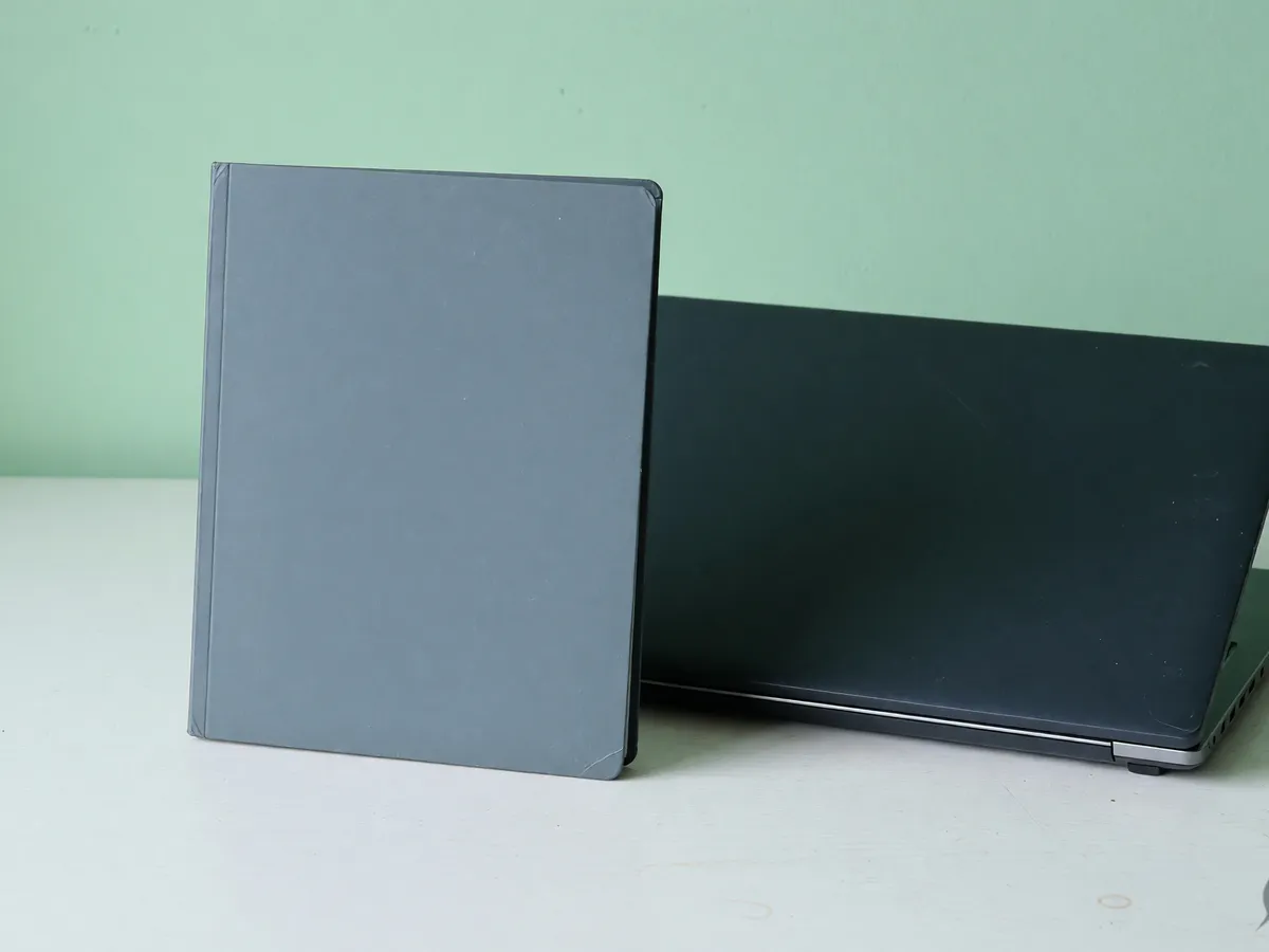 Closed grey return folder standing beside a dark closed laptop