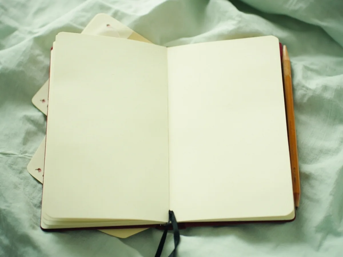 Open unlined notebook with blank cream pages and a wooden pencil