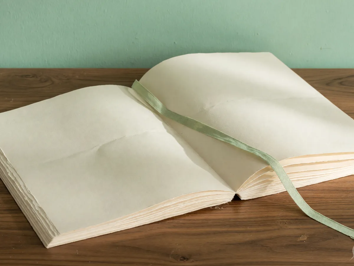 Open blank scoring folio with a sage ribbon on a wooden desk