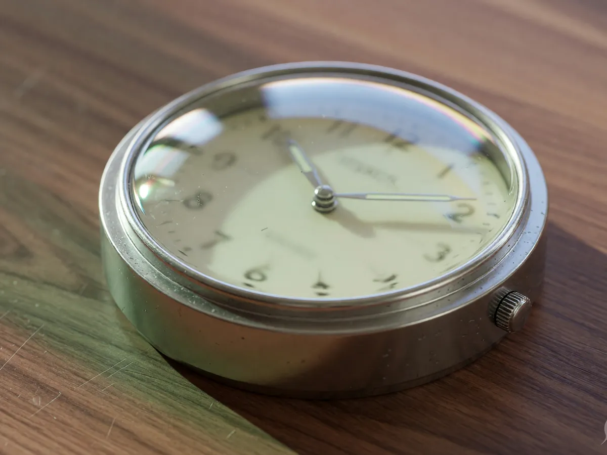 Round analog desk clock on walnut with an unreadable face